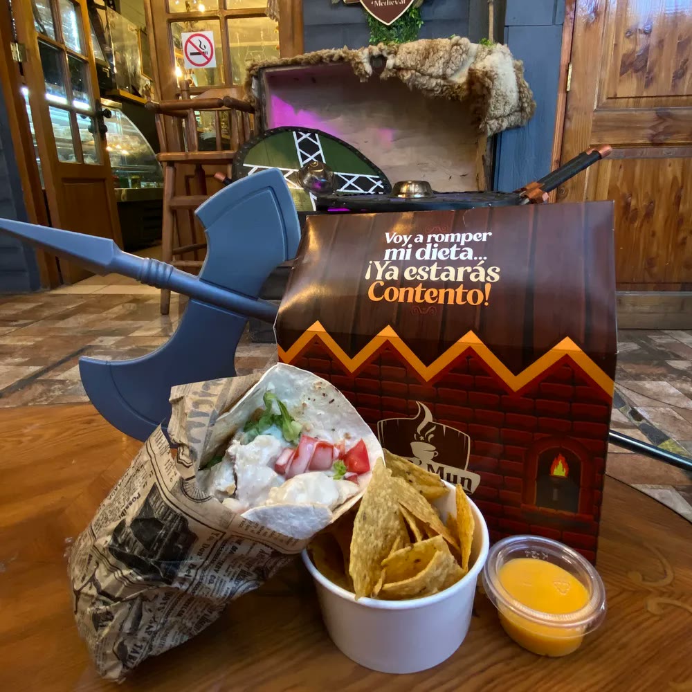 Cajita Medieval Feliz: caja ilustrada, wrap, nachos con salsa de queso y un hacha de juguete clavada al lado
